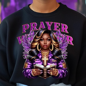 May include: A black sweatshirt with a purple and gold design featuring a woman with a bible and the text "PRAYER WARRIOR".