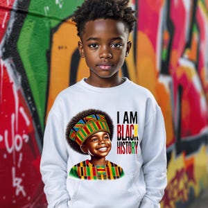May include: A white sweatshirt with a colorful illustration of a young boy wearing a crown and the text "I AM BLACK HISTORY".