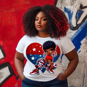 May include: A white t-shirt with a red, white, and blue heart design featuring a cartoon girl with a red shirt, blue camo pants, and hoop earrings. The heart is filled with glitter and stars.