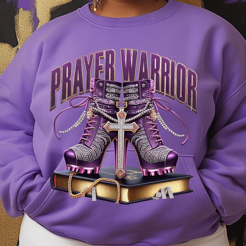 May include: Purple sweatshirt with the text "PRAYER WARRIOR" in gold lettering. The sweatshirt features a pair of purple high-heeled boots with rhinestones and a gold cross.