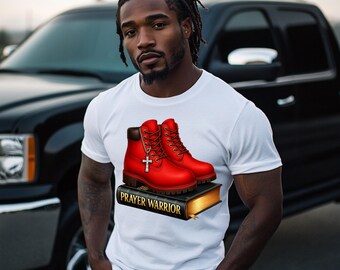 May include: White t-shirt with a graphic of red boots and a cross pendant, on a book with "PRAYER WARRIOR". The boots have brown details and laces. The shirt is worn by a person.