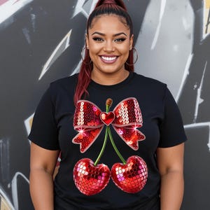 May include: Black t-shirt featuring a red sequined cherry and bow design. The cherries have a shiny, sparkly finish.