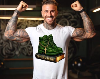 May include: White t-shirt with a graphic of green camouflage boots adorned with a gold chain and cross, placed on a book with the text "PRAYER WARRIOR". The boots have a gold chain and cross.