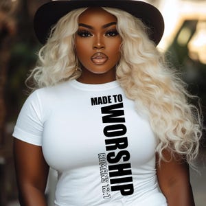 May include: White t-shirt with black text that reads "Made to Worship Romans 12:1"