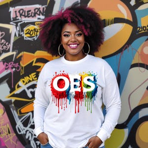 May include: White long-sleeve sweatshirt with a colorful paint splatter design featuring the letters "OES" in white.