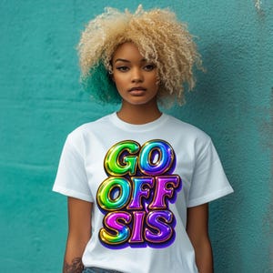 Può includere: T-shirt bianco con la scritta "GO OFF SIS" in lettere a bolle colorate e contorno dorato. Il testo ha un effetto 3D. La maglietta a maniche corte è indossata da una persona con capelli biondi e turchesi.