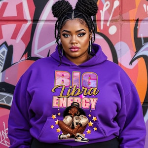 May include: Purple hoodie with the text "BIG Libra ENERGY" in gold and pink lettering. A cartoon illustration of a woman with a gold star background.
