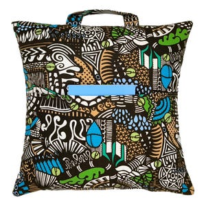 May include: A black and white patterned pillow with blue, green, and brown accents. The pillow has a blue zipper pocket and a brown handle.