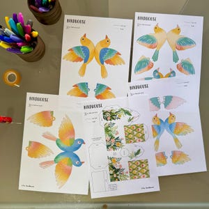 May include: Printable birdhouse craft templates featuring colorful birds with cut-out wings. The templates include instructions to "Cut, fold and stick" and are labeled "Birdhouse".