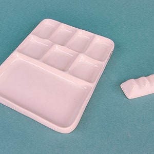 May include: White ceramic paint palette with nine separate wells, including a large mixing area. A small white ceramic palette knife is also included.