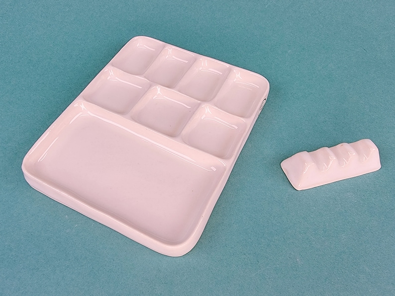 May include: White ceramic paint palette with nine separate wells, including a large mixing area. A small white ceramic palette knife is also included.