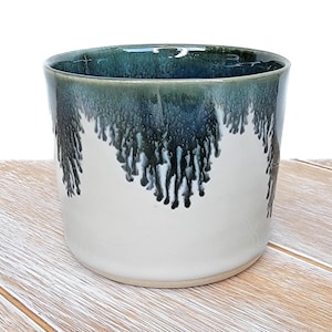 May include: A white ceramic planter with a blue and green glaze. The glaze has a drip effect, creating a unique and artistic look.