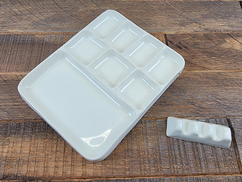 May include: White ceramic paint palette with nine wells and a large mixing area. A small white ceramic palette knife is also included.