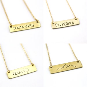 K&ouml;nnte beinhalten: Vier goldene Halsketten mit verschiedenen rechteckigen Anh&auml;ngern. Die Anh&auml;nger zeigen den Text "Mama Bird", "Ew, People", "Texas" mit einer Umrandung des Bundesstaates und einem Bergketten-Design.