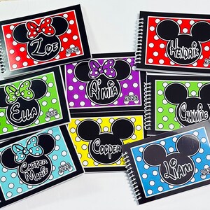 Pode incluir: Sete cadernos de espiral pretos com capas de bolinhas coloridas que apresentam uma silhueta do Mickey Mouse ou da Minnie Mouse. Cada caderno tem um nome e o ano 2023 impresso na capa.