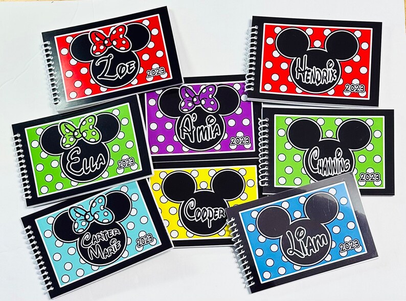 Pode incluir: Sete cadernos de espiral pretos com capas de bolinhas coloridas que apresentam uma silhueta do Mickey Mouse ou da Minnie Mouse. Cada caderno tem um nome e o ano 2023 impresso na capa.