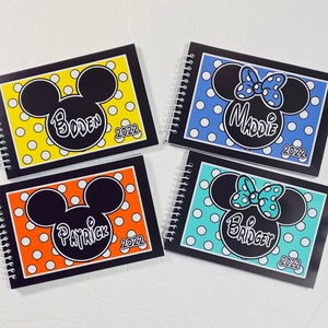 Pode incluir: Quatro cadernos negros com espiral com um design de Mickey Mouse ou Minnie Mouse. Cada caderno tem um fundo de cor diferente e um nome diferente: Boden, Maddie, Patrick e Bridget. O ano de 2022 est&aacute; impresso em cada caderno.