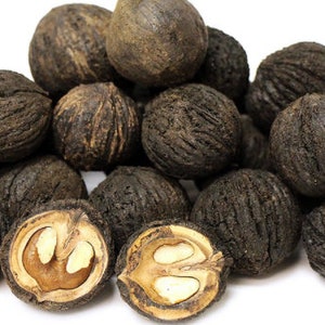 May include: A group of black walnut shells, some with the outer husk still attached, and some with the shell cracked open to reveal the nut inside.