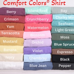 May include: A stack of folded t-shirts in various colours, including berry, crimson, yam, terracotta, mustard, banana, ivory, white, island reef, crunchberry, watermelon, blossom, orchid, violet, chambray, blue jean, bay, chalky mint, seafoam, light green, moss, blue spruce, espresso, black, and pepper. The shirts are labelled with their colour names.