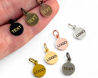 May include: Assortment of small round metal tags with jump rings. The tags are in various finishes, including gold, silver, black, and copper. The tags are engraved with the words "TEXT" and "LOGO".