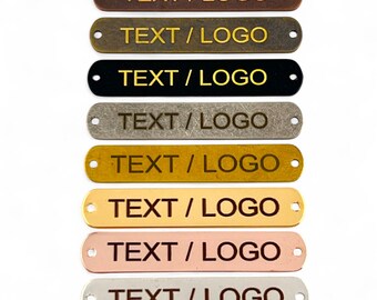May include: Eight metal tags with a hole at the top. The tags are in different colours: copper, brass, black, silver, gold, rose gold, and silver. Each tag has the text "TEXT/LOGO" engraved on it.