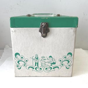 May include: A vintage white and green storage box with a metal clasp and handle. The box features a green band around the top and a decorative green illustration of a band playing music on the front. The box is likely for storing records or other items.