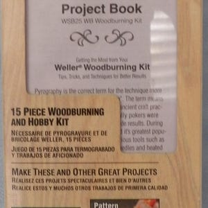 May include: A Weller 15-piece woodburning and hobby kit in a rectangular box. The packaging features the Weller logo, the text Project Book WSB25 WB Woodburning Kit, and images demonstrating woodburning, pattern transfers, leather work, and cutting foam.