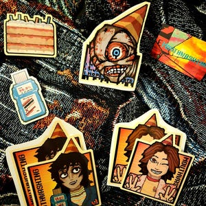 May include: A set of five stickers featuring various characters and designs. The stickers are printed on white paper with a glossy finish. The stickers include a birthday cake, a character with a single eye, a bottle of mouthwash, and two characters with party hats.