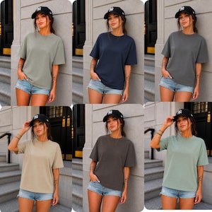 May include: Six short-sleeved t-shirts in different solid colours: olive green, navy blue, charcoal grey, tan, dark brown, and light green. Each shirt is worn with denim shorts and a black baseball cap.