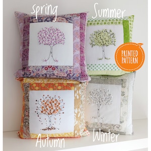 May include: Four decorative cushion covers with embroidered trees representing the four seasons. The cushions are made of patchwork fabric with different colours and patterns. The cushion covers are labelled "Spring", "Summer", "Autumn", and "Winter".