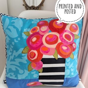 May include: Cushion with a floral design. The pillow features a vibrant bouquet in a black and white striped vase against a turquoise background. The text "PRINTED AND POSTED" is in a speech bubble.