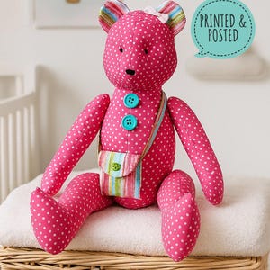 May include: A pink teddy bear covered in white polka dots, with a small striped bag and turquoise buttons. The bear has striped ears and a white bow. The text "PRINTED & POSTED" is in a speech bubble.