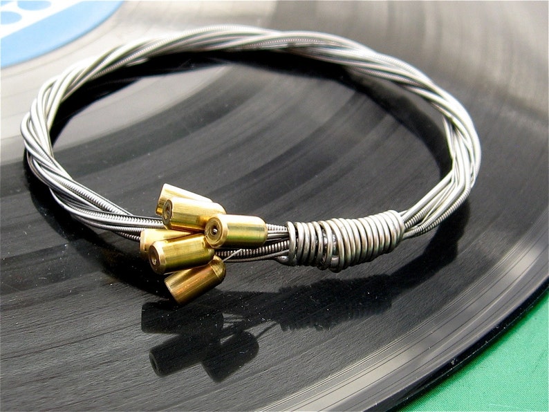 May include: A silver guitar string bracelet with a cluster of gold-toned metal beads.