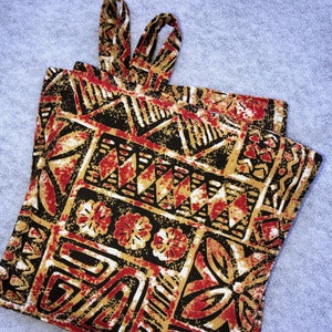 May include: Two brown and red patterned pot holders with a geometric design. The pot holders have a loop handle.