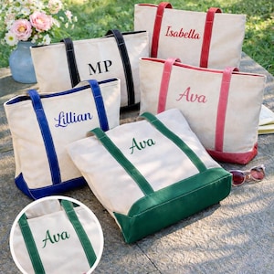 May include: Five canvas tote bags with different colored trim and handles. Each bag has a name or initials embroidered on the front in a matching color. The bags are beige with black, blue, green, and red accents. One bag has the initials "MP".