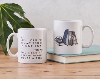 May include: Two white coffee mugs with black text and illustrations. The mug on the left says "ME: SEE, I CAN FIT ALL MY BOOKS IN ONE BOX! THEM: YOU NEED TO STOP CALLING YOUR HOUSE A BOX.". The mug on the right has an illustration of a stack of books and a pair of glasses.