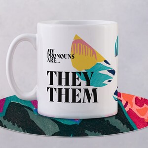 May include: White ceramic mug with a colorful abstract design and the text "My pronouns are... They Them" printed on the front.