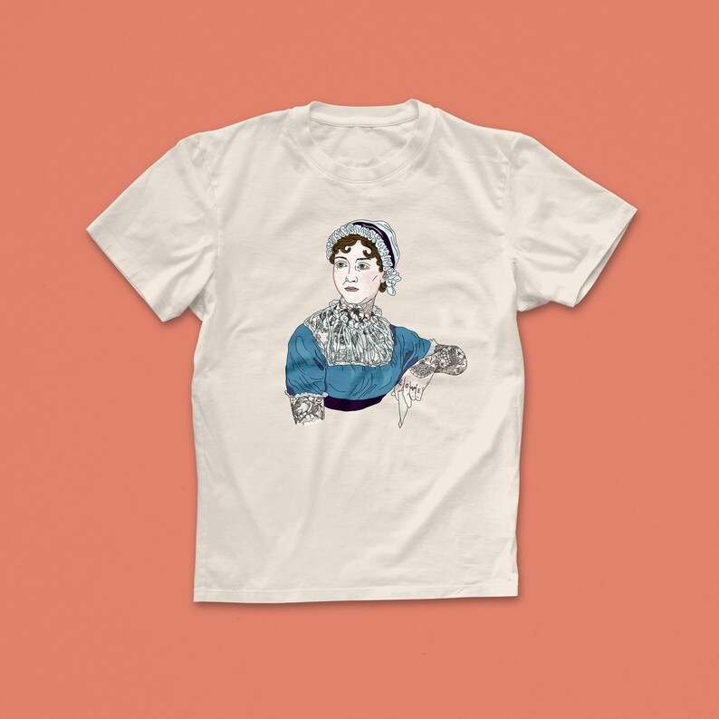 Pu&ograve; includere: Una maglietta bianca con una grafica di Jane Austen con tatuaggi. La grafica &egrave; a colori e mostra Austen con un vestito blu e un cappello bianco.