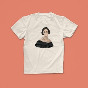 Pu&ograve; includere: Una maglietta bianca con un'illustrazione in bianco e nero di una donna con un tatuaggio sul petto.