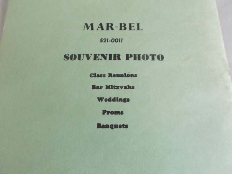 May include: A green paper flyer with the text "MAR-BEL 521-0011 SOUVENIR PHOTO" and a list of events: Class Reunions, Bar Mitzvahs, Weddings, Proms, Banquets.