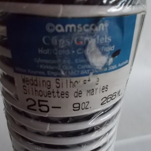 May include: A package of 25 white plastic wedding cake toppers with black silhouettes of brides and grooms. The package says "Wedding Silhouettes" and "Silhouettes de maries" in black text. The package also says "25- 9 oz. 266 ML."