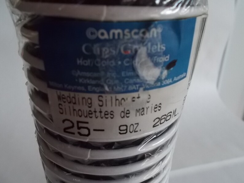 May include: A package of 25 white plastic wedding cake toppers with black silhouettes of brides and grooms. The package says "Wedding Silhouettes" and "Silhouettes de maries" in black text. The package also says "25- 9 oz. 266 ML."