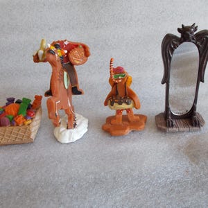 May include: A collection of Halloween-themed figurines. Includes a basket of candy, a headless horseman, a gingerbread man with a donut float, and a bat-winged mirror. The figurines are primarily brown, orange, and white.