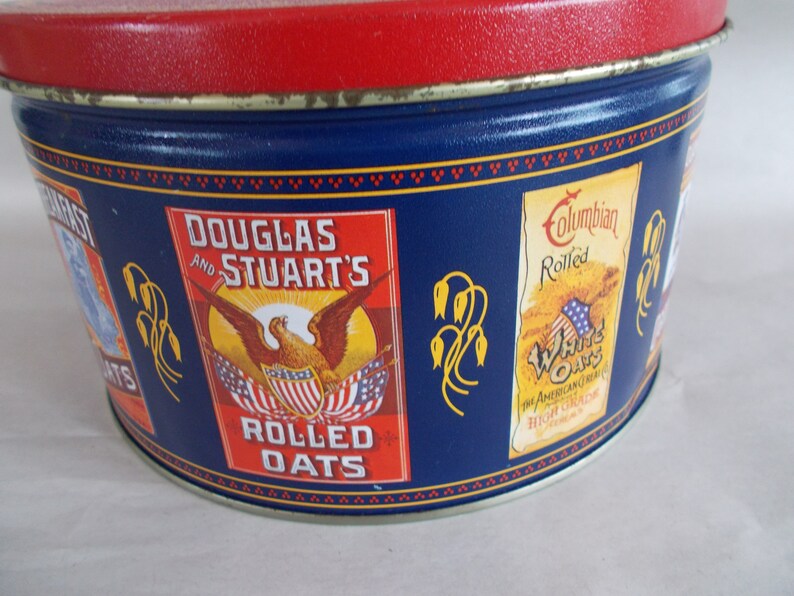 Op de afbeelding: Een vintage blauwe en rode blikken container met een Amerikaanse adelaar en de tekst "Douglas and Stuart's Rolled Oats". De blik heeft ook een rood, wit en blauw ontwerp met de tekst "Columbian Rolled White Oats The American Cereal High Grade".