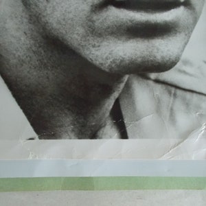 May include: Black and white photograph of a man's face and upper torso. The man is wearing a white shirt and has a serious expression on his face.