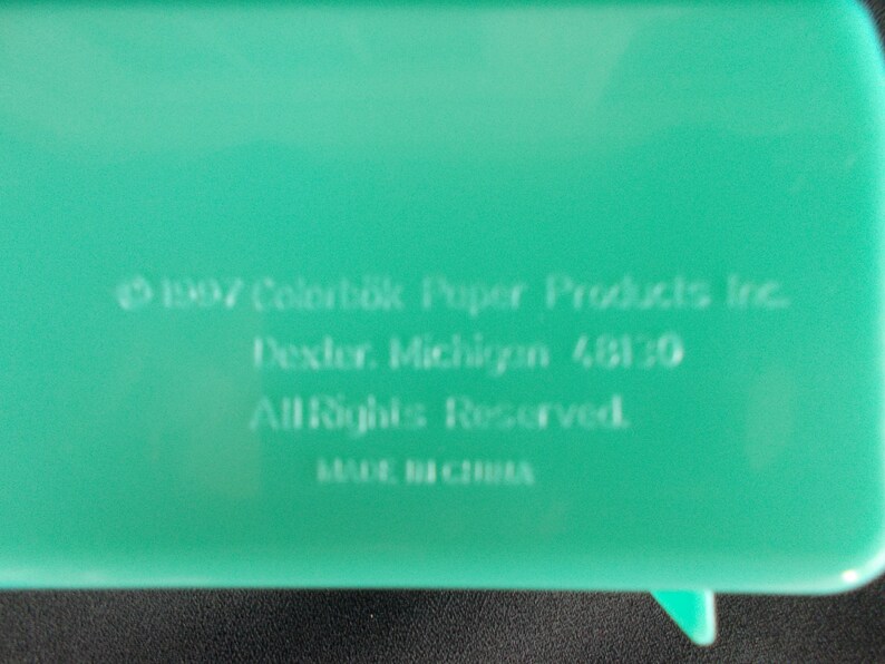 May include: A green plastic container with the text "1997 Colorbok Paper Products Inc. Dexter, Michigan 48130 All Rights Reserved. MADE IN CHINA" printed on the bottom.
