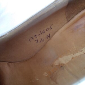 May include: Interior view of a shoe, showing the insole with handwritten markings. The markings include the numbers "172-1605" and "7 1/2 N". The shoe's interior is a light tan color.