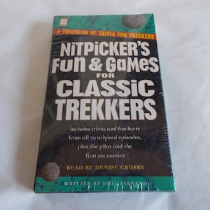 May include: A book titled "Nitpicker's Fun & Games for Classic Trekkers" with a teal and black cover. The book includes trivia and fun facts from the original episodes and movies. The author's name is Denise Crosby.