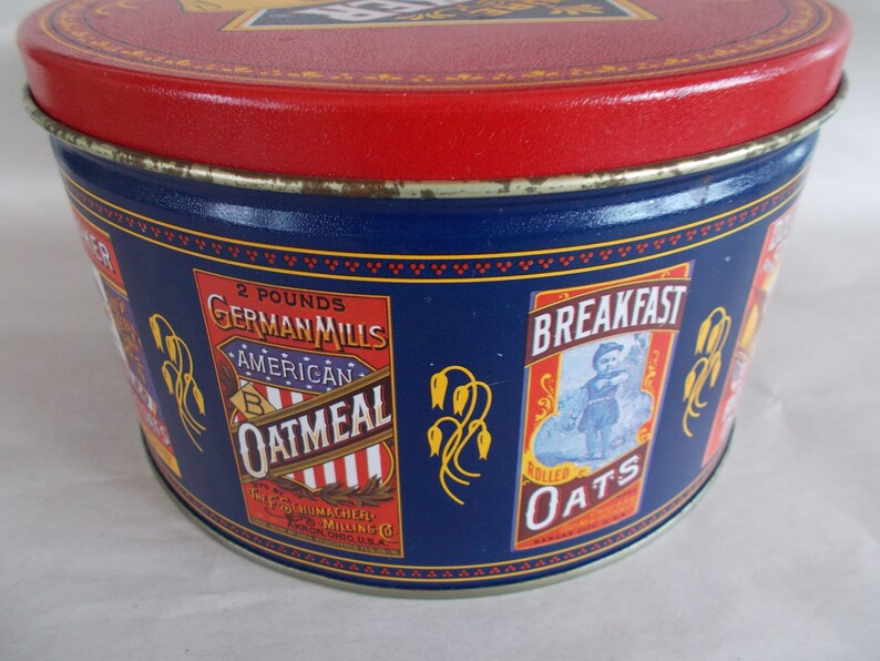 Op de afbeelding: Blauwe en rode blik met een etiket met de tekst "2 pounds German Mills American Oatmeal" en een ander etiket met de tekst "Breakfast Rolled Oats".