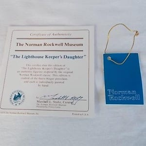 May include: A certificate of authenticity for a porcelain figurine of "The Lighthouse Keeper's Daughter" by Norman Rockwell. The certificate is printed on white paper with blue and gold accents. The certificate is signed by Marshall L. Stoltz, Curator of the Norman Rockwell Museum.